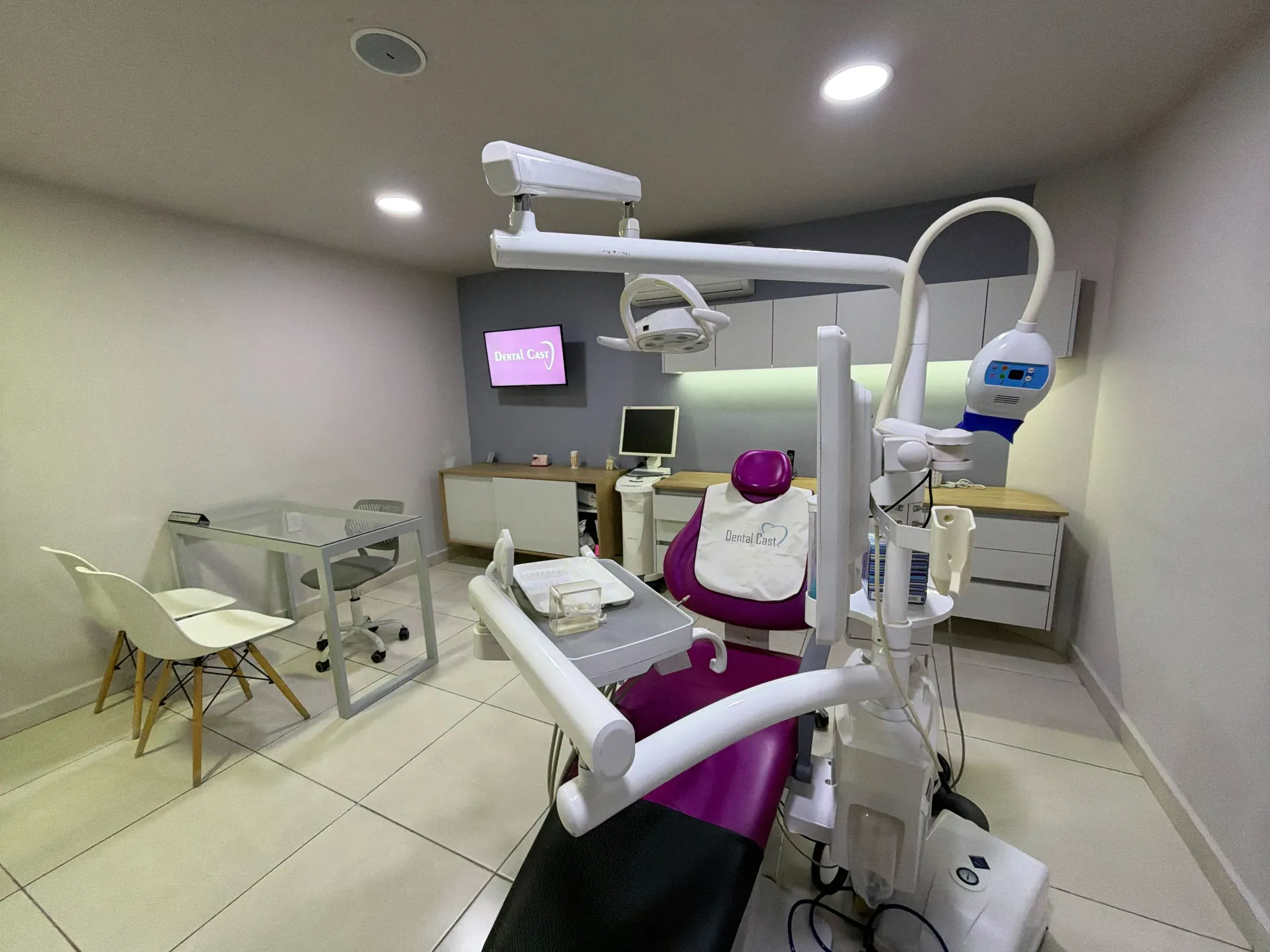 Consultorio de Dental Cast con el logotipo de la clínica en pantalla y sillón dental