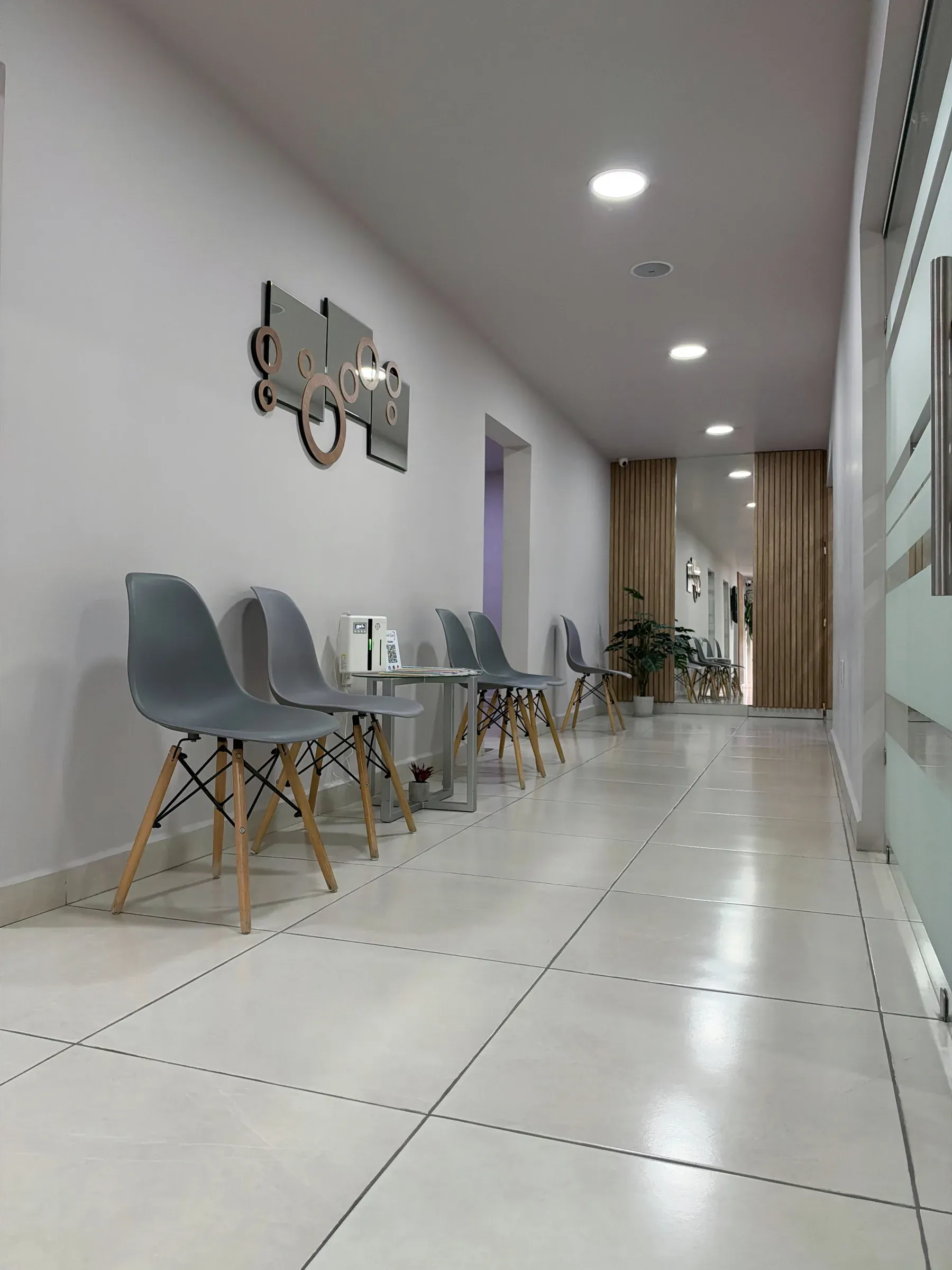 Sala de espera de Dental Cast en el pasillo, con sillas grises y una mesa auxiliar