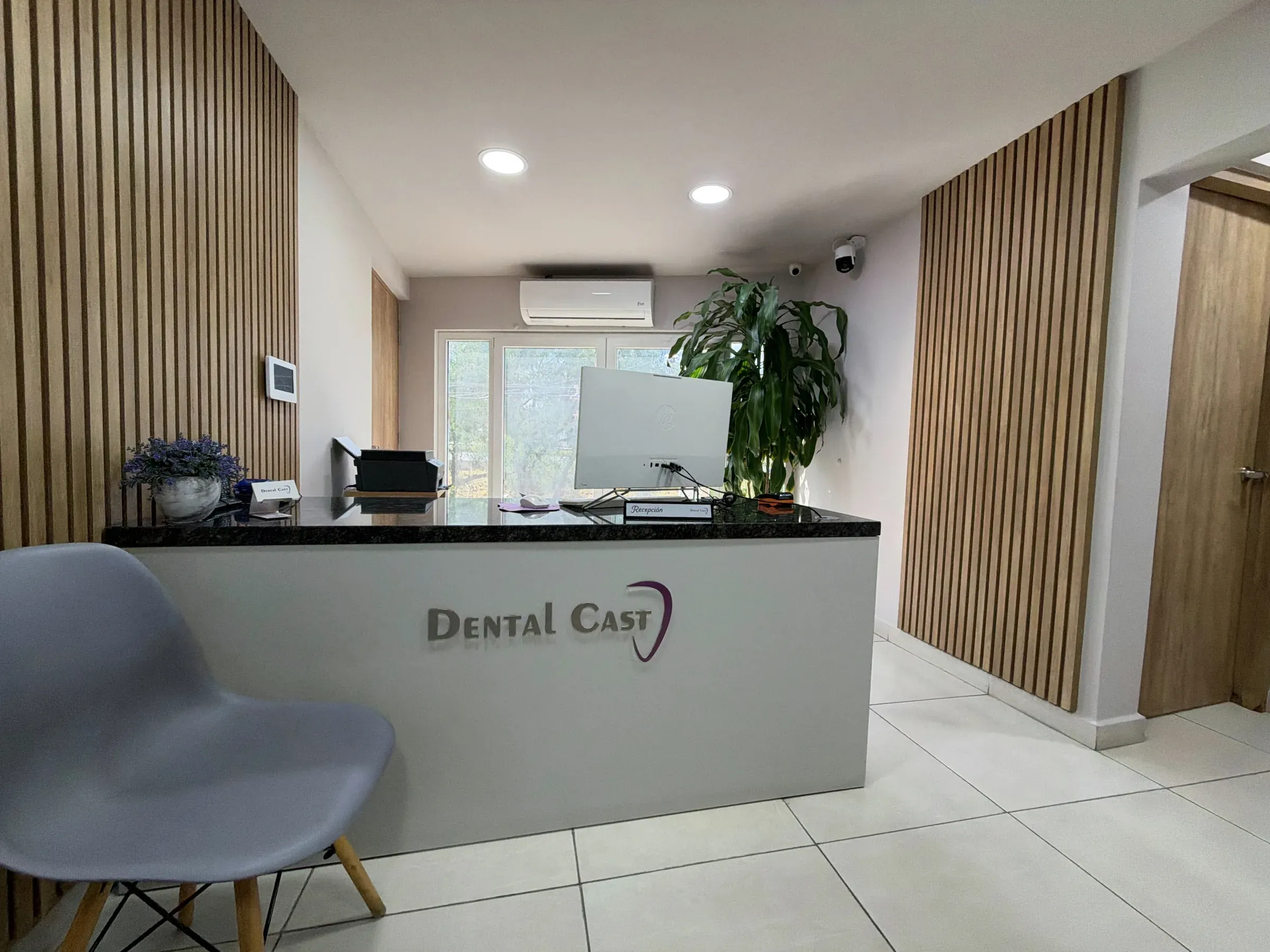 Recepción de Dental Cast con el logotipo de la clínica en el mostrador
