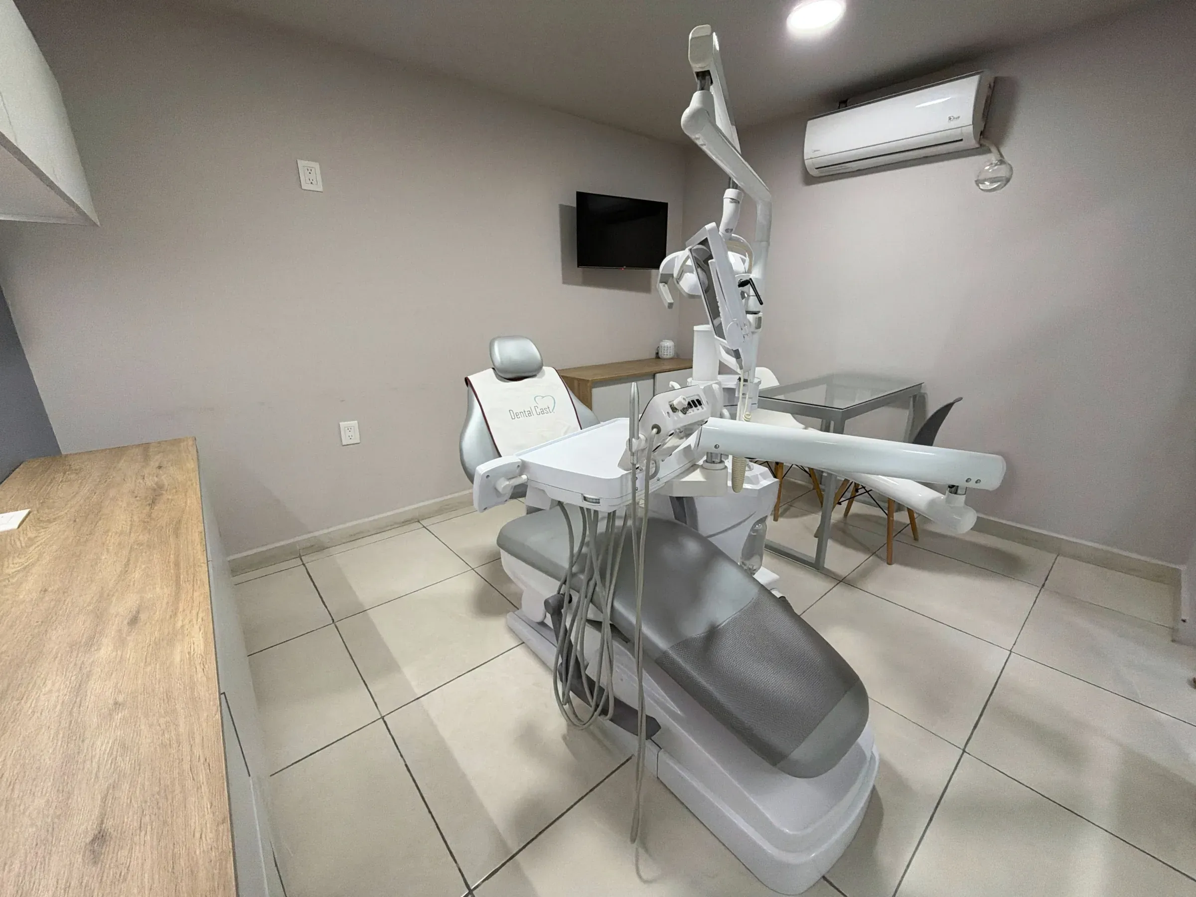 Consultorio de Dental Cast con sillón gris, escritorio de cristal y sillas