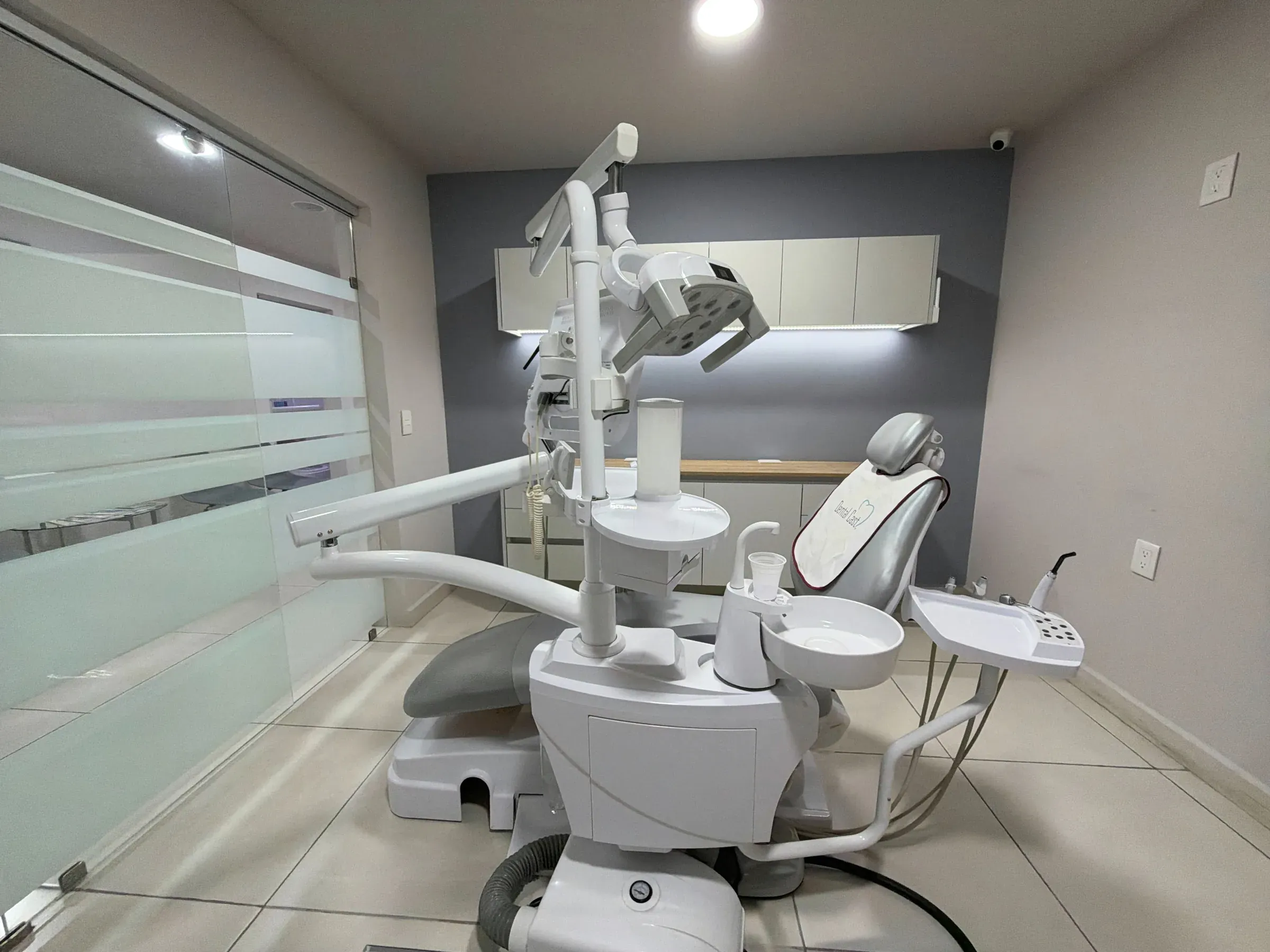 Consultorio de Dental Cast con sillón gris y cancel de cristal esmerilado