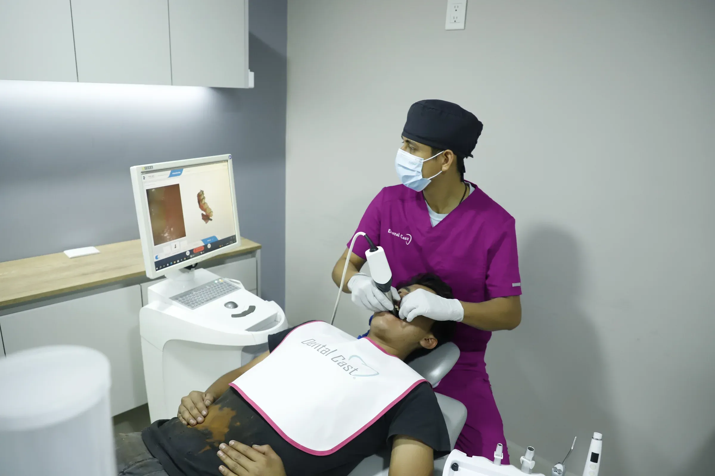 Integrante del equipo de Dental Cast escanea la boca de un paciente mientras revisa el modelo 3D en el monitor