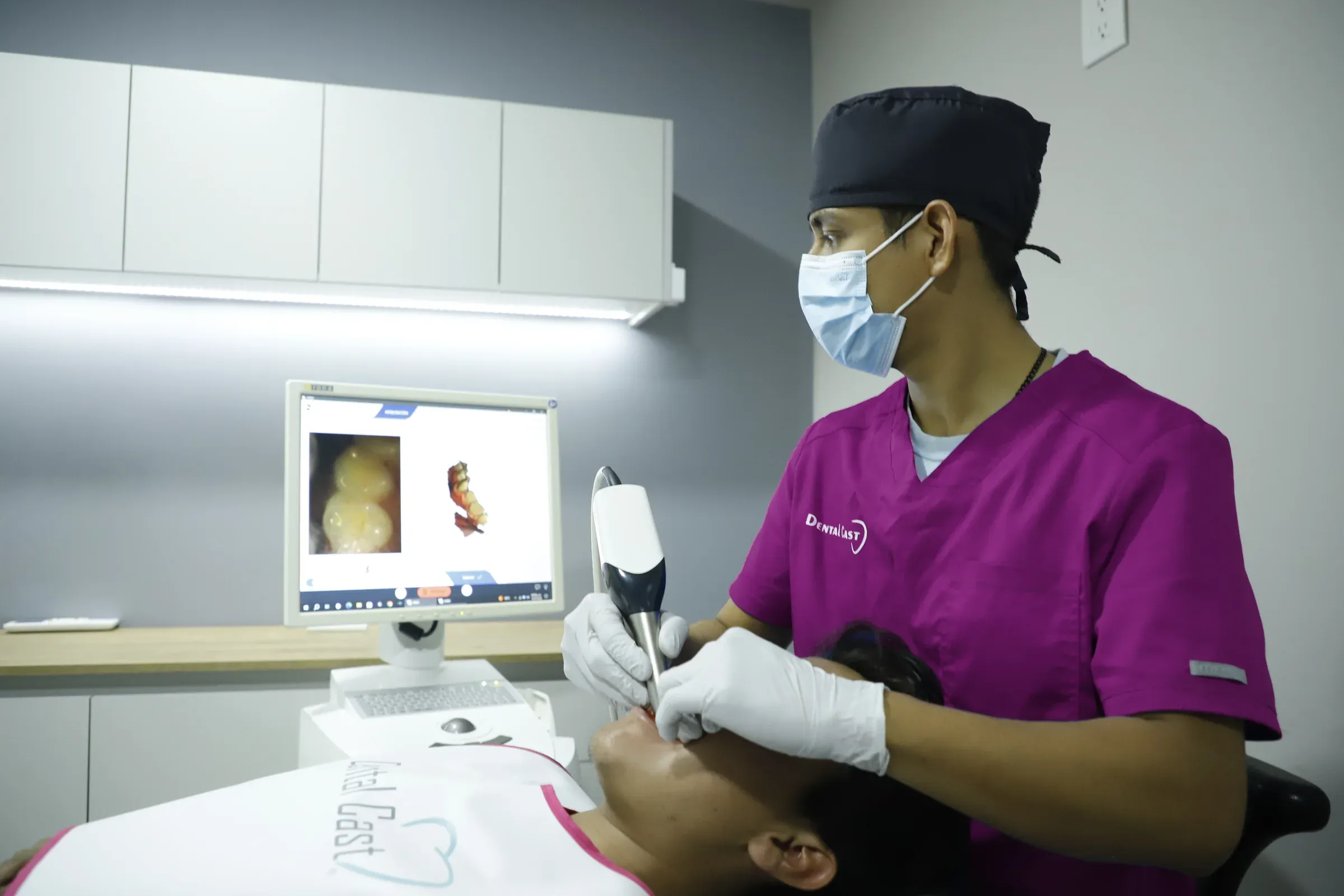 Integrante del equipo de Dental Cast usa el escáner intraoral con el modelo 3D de los dientes en el monitor