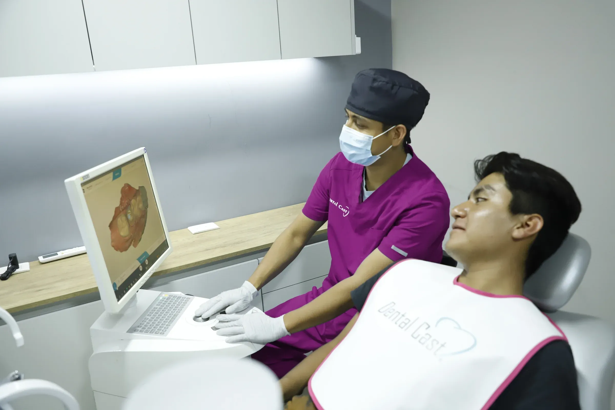 Integrante del equipo de Dental Cast explica a un paciente su escaneo 3D en el monitor